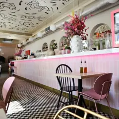 Stylowe wnętrze restauracji w Warszawie z różowym neonem i czarno-białą szachownicą na podłodze. Idealne miejsce na listę "top 10 restauracji Warszawa".