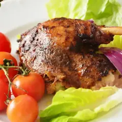 Chrupiąca kaczka w pomarańczach, podana z pomidorkami, sałatą i czerwoną cebulą.