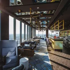 Nowoczesna restauracja z widokiem na miasto, z barem i wygodnymi fotelami.