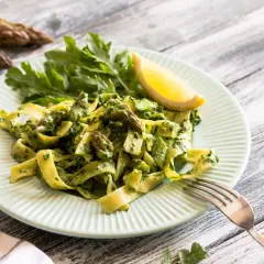 Pappardelle z zielonym sosem, szparagi i rukola na talerzu. Pyszny makaron ze świeżymi warzywami.