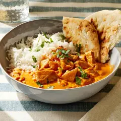 Miseczka pełna aromatycznego kurczaka butter chicken z ryżem i chlebkiem naan.