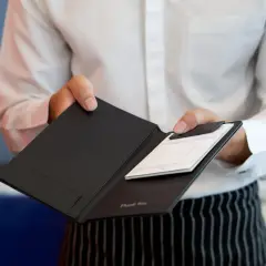 Kelner podaje rachunek do zapłaty, ułatwiając dzielenie rachunku w restauracji.