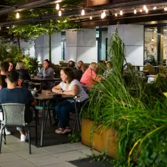 Wieczorny relaks w jednej z nowych restauracji w Łodzi. Ludzie siedzą przy stolikach, delektując się posiłkami i rozmowami.