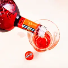 Czerwony Martini Fiero nalewany do szklanki, obok leży zakrętka. Idealny na orzeźwiający drink z tonikiem.