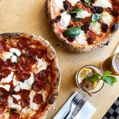 Dwie pyszne pizze, jedna z salami, druga z pomidorami i mozzarellą, idealne na najlepszą pizzę Warszawa. Do tego orzeźwiające napoje.