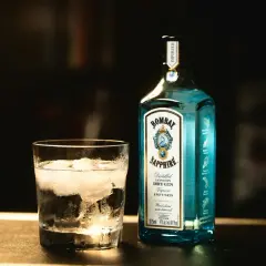Szklanka z lodem i butelka Bombay Sapphire gin. Idealny na orzeźwiający bombay sapphire drink.