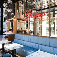 Elegancka restauracja z owocami morza w Warszawie. Neonowy napis "Lobster" nad błękitnymi kanapami.