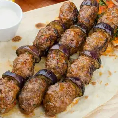 Grillowane szaszłyki z mielonego mięsa i bakłażana, czyli pyszna kofta libańska, podane na chlebku z sosem.