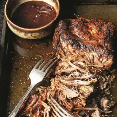 Soczysta, szarpana wieprzowina z sosem barbecue na blasze. Widoczne widelce ułatwiające rozrywanie mięsa.