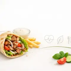 Czy kebab jest zdrowy? Na zdjęciu soczysty kebab z warzywami, frytki i sos. Obok symbole zdrowia i świeżych składników.