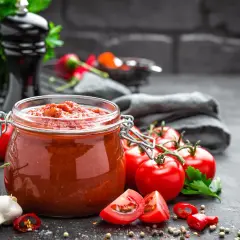 Słoik domowego sosu pomidorowego, świeże pomidory, czosnek i papryczki chili. Idealne dania z pomidorów na każdą okazję.