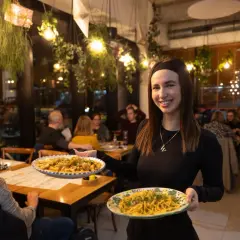 Uśmiechnięta kelnerka serwuje pyszne dania w najlepszej włoskiej restauracji we Wrocławiu. Aromatyczne makarony kuszą z talerzy.