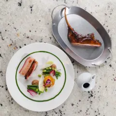 Wykwintne danie z żeberkami i warzywami, podane na talerzu i metalowej tacce, jak u Senwickich menu.