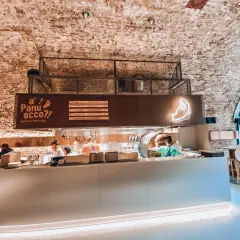 Wnętrze jednej z nowych restauracji w Warszawie. Widać piec do pizzy, bar i gości.