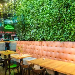 Wnętrze restauracji z zieloną ścianą, neonem "Viña Esmeralda" i wygodnymi lożami. Idealne miejsce na liście top 10 restauracji w Krakowie.