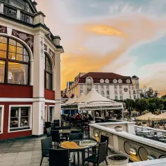 Eleganckie tarasy z widokiem na morze, idealne na kolację w jednej z nowych restauracji w Gdańsku. Zachód słońca maluje niebo na pomarańczowo.