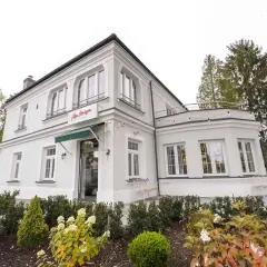Elegancka willa z napisem "La Maison" Michel Moran. Piękny ogród przed budynkiem.