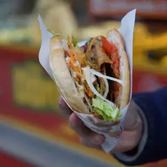 Ręka trzyma pysznego kebaba, pełnego mięsa, warzyw i sosu. To musi być najlepszy kebab Szczecin!
