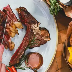 Soczysty stek T-bone, pokrojony w plastry, z pieprzem i rozmarynem. Idealny wybór, jeśli zastanawiasz się, jakie wino do steka.