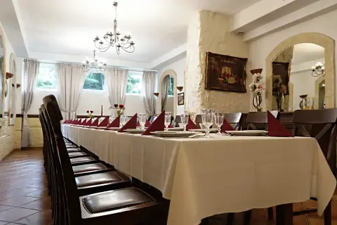 Długi stół w restauracji, nakryty białym obrusem, z czerwonymi serwetkami i kieliszkami. Czy rezerwacja stolika w restauracji jest płatna?