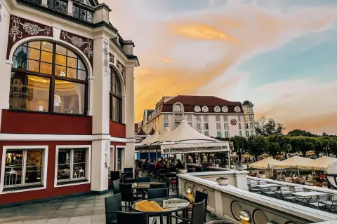 Eleganckie tarasy z widokiem na morze, idealne na kolację w jednej z nowych restauracji w Gdańsku. Zachód słońca maluje niebo na pomarańczowo.