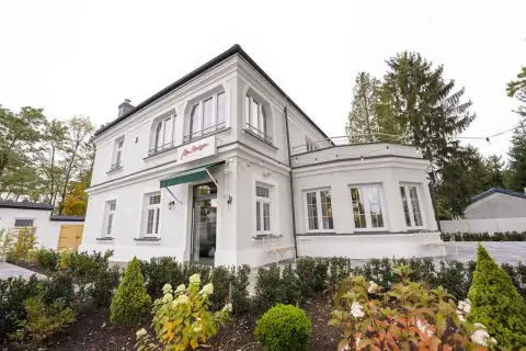 Elegancka willa z napisem "La Maison" Michel Moran. Piękny ogród przed budynkiem.