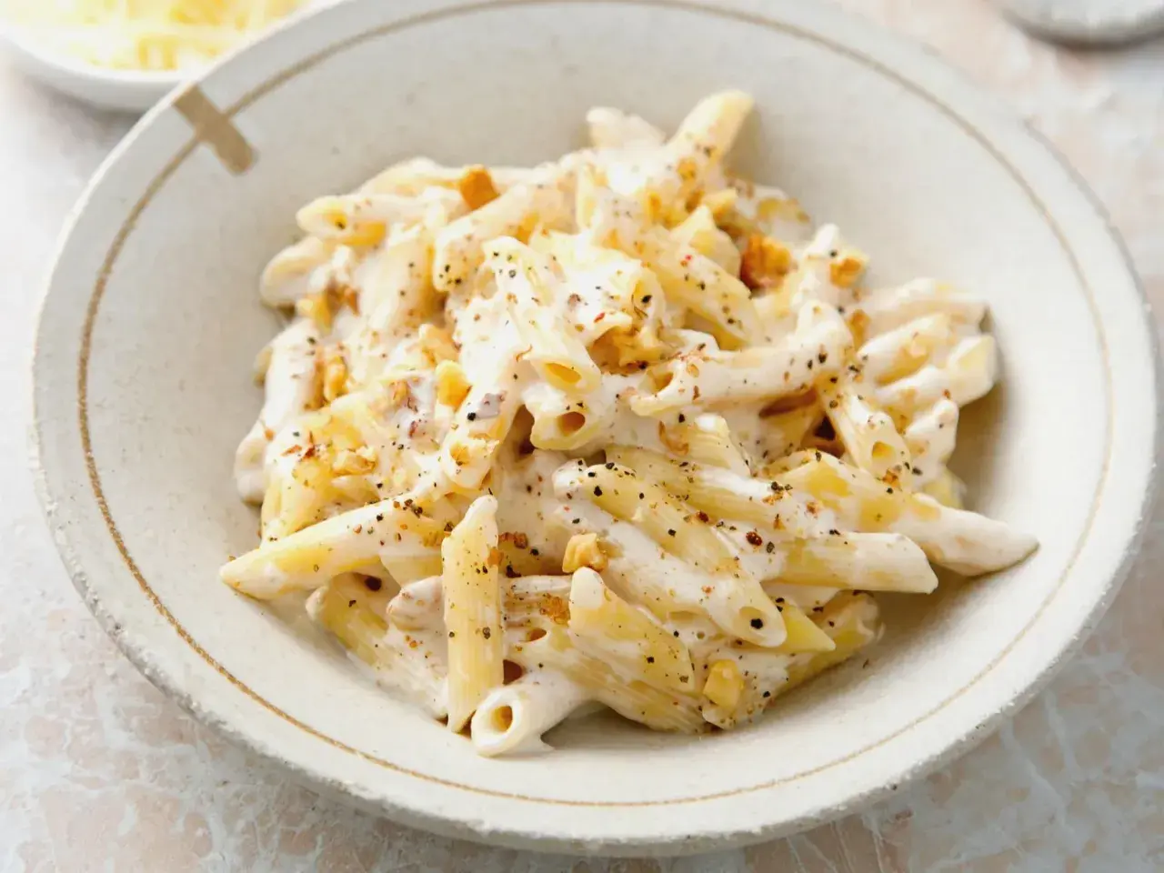 Penne w kremowym sosie z orzechami włoskimi, posypane pieprzem. Pyszne danie, które zachwyci każdego smakosza.