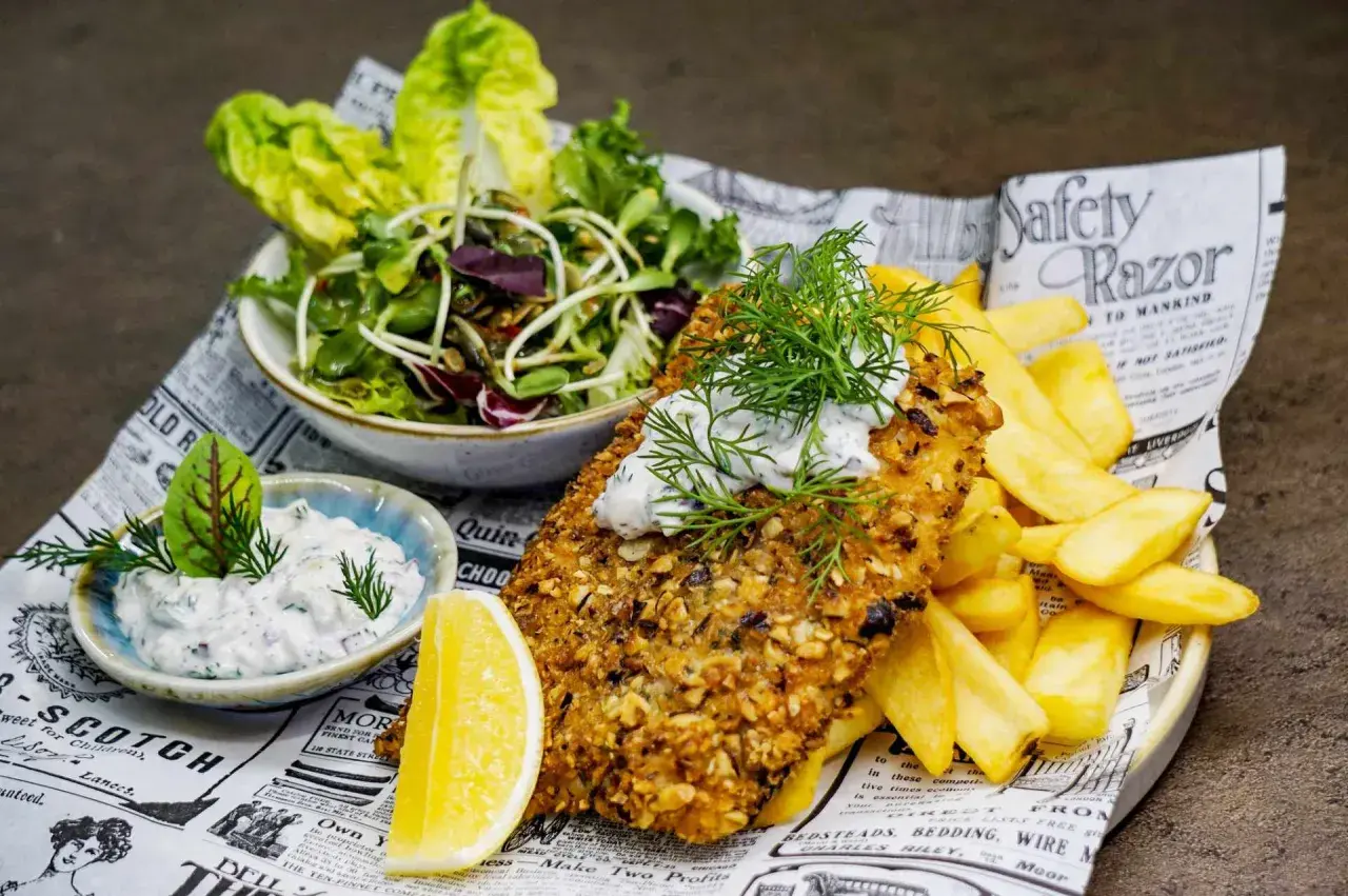 Ryba w panierce z orzechów, frytki, sałatka i sos – idealne danie, które mogłoby znaleźć się w rankingu 10 najlepszych restauracji w Kielcach.