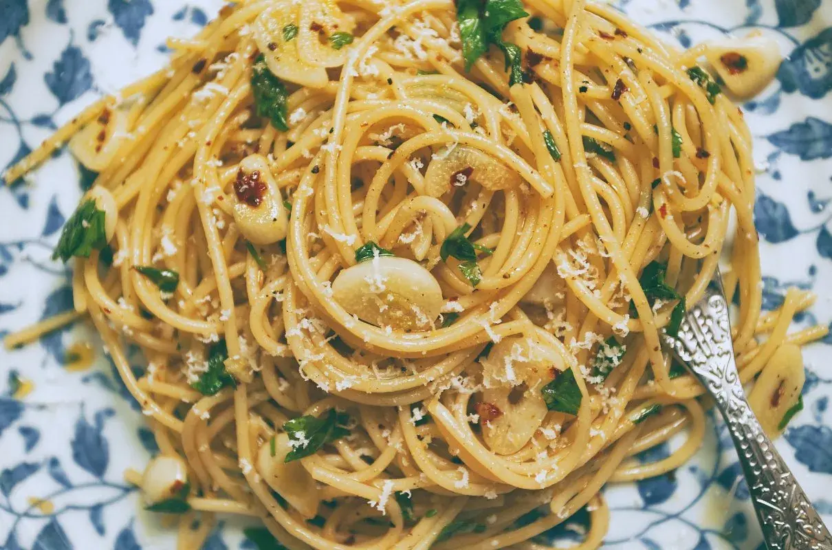 Pyszny makaron aglio olio z czosnkiem, natką pietruszki i płatkami chili, posypany parmezanem.