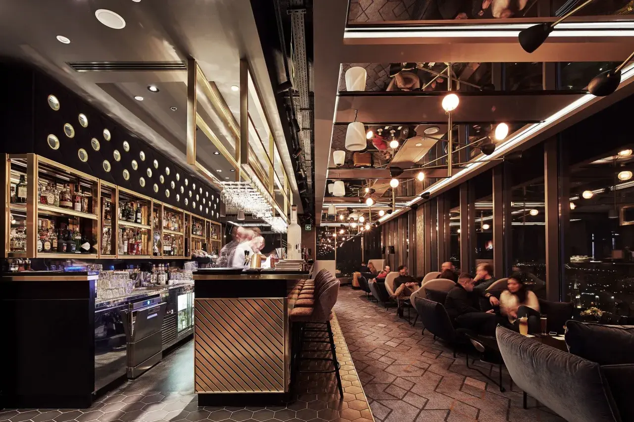 Elegancki bar i wygodne fotele tworzą klimatyczne restauracje Katowice. Goście relaksują się przy widoku na nocne miasto.