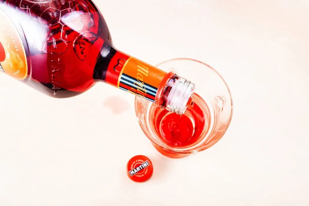 Czerwony Martini Fiero nalewany do szklanki, obok leży zakrętka. Idealny na orzeźwiający drink z tonikiem.