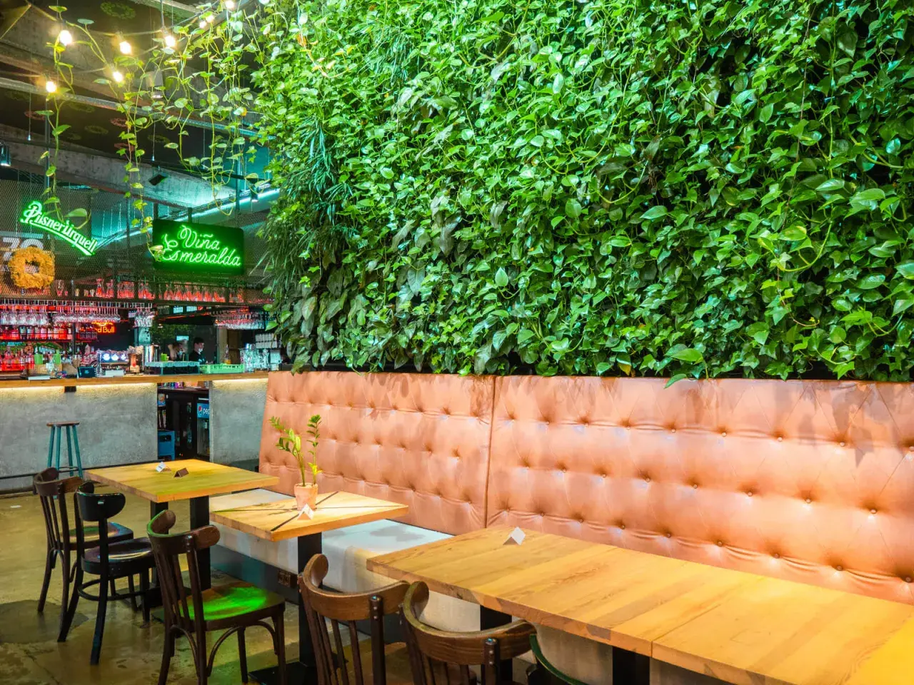 Wnętrze restauracji z zieloną ścianą, neonem "Viña Esmeralda" i wygodnymi lożami. Idealne miejsce na liście top 10 restauracji w Krakowie.