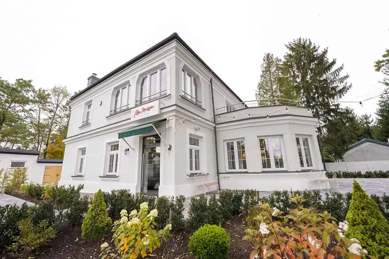 Elegancka willa z napisem "La Maison" Michel Moran. Piękny ogród przed budynkiem.
