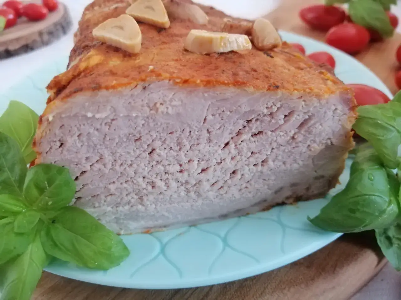 Soczysty schab w marynacie, pieczony z czosnkiem i ziołami, podany z pomidorkami koktajlowymi.