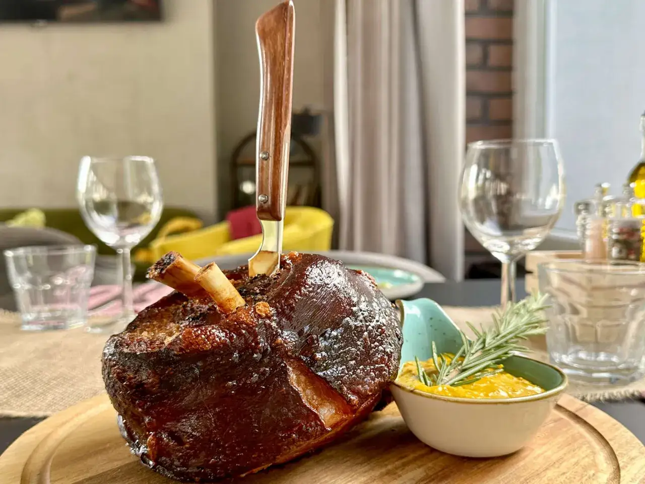 Soczysta golonka z nożem wbitym w mięso, podana z sosem i rozmarynem. Idealna uczta w jednej z najlepszych restauracji na Śląsku.
