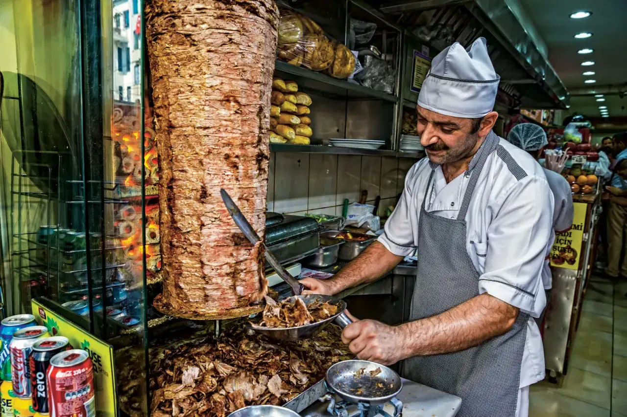 Kucharz kroi mięso z ogromnego rożna, przygotowując prawdopodobnie pierwszy kebab w Polsce.